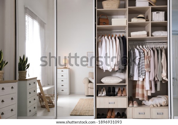 Wardrobe closet with different stylish clothes,\
shoes and home stuff in\
room