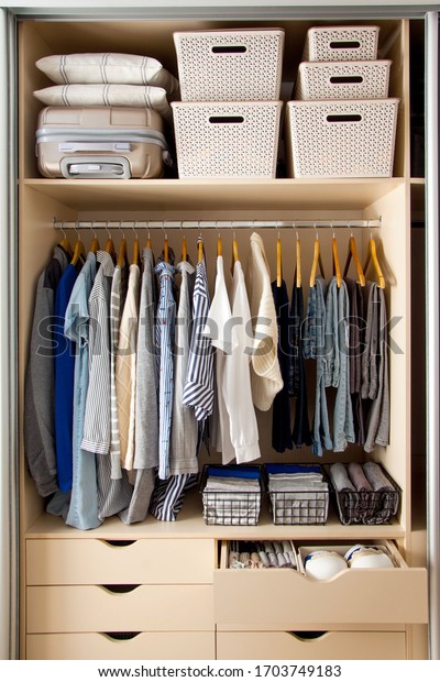 Wardrobe with perfect order clothes in blue\
and light shades on the hangers and things in containers. The\
concept of organizers and cleanliness in the\
house