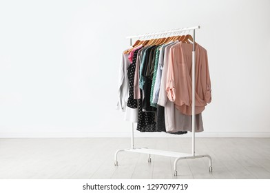 Wardrobe rack with stylish clothes near white wall indoors. Space for text - Shutterstock ID 1297079719