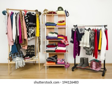 Wardrobe With Winter Clothes Nicely Arranged. Dressing Closet With Colorful Clothes And Accessories On Hangers And A Shelf.