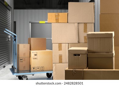 Warehouse with boxes. Storage space. Cardboard boxes in warehouse corridors. Building with separate storage units. Building with storage units without people. Cargo trolley with parcels. 