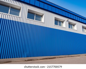 Warehouse Building Outside. A Blue-and-white Hangar With Windows. Warehouse Of An Industrial Enterprise. Storage Space For Goods. Rent A Warehouse. Modern Appearance Of An Industrial Building.