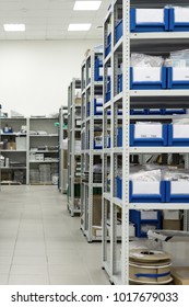 Warehouse of components for the electronics industry. White metal racks with blue plastic trays installed in them.