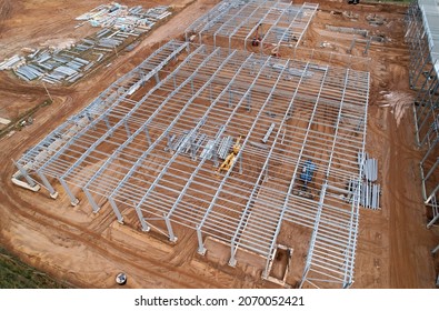 Warehouse Construction from metal structure. Industrial building on light gauge steel framing. Frame of modern hangar or factory. Construction site with steel structure warehouse. Top view on a roof. - Shutterstock ID 2070052421