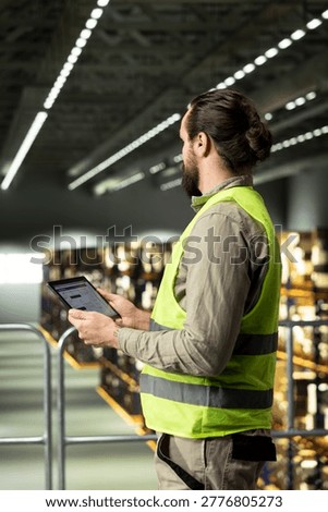 Warehouse employee, tracking software, tablet in warehouse, standing on platform and ensuring express delivery for order fulfillment. Airway bill data for e-commerce operations.