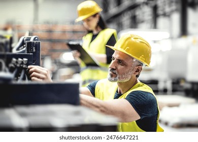 Warehouse employees in warehouse. Two workers in reflective clothing in modern industrial factory, heavy industry, manufactrury. - Powered by Shutterstock