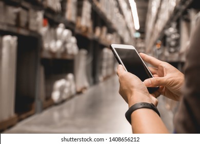 Warehouse factory contact with mobile cell phone. Man hand holding cell phone checking factory warehouse management, person smart logistic mobile industry using phone and internet control business.