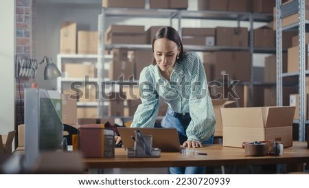 Warehouse Female Inventory Manager Using Laptop Computer, Preparing a Small Parcel for Postage. Young Confident Small Business Owner Working in Storeroom, Preparing Order for Client.
