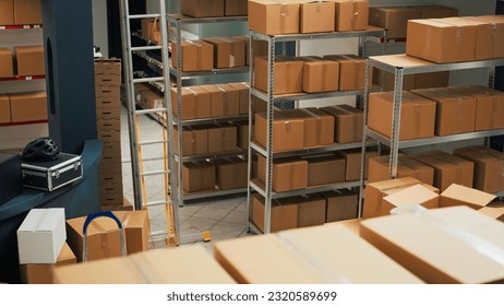 Warehouse filled with raw materials and racks to put cardboard boxes, preparing packages with merchandise and products for shipping. Empty storage room used for quality control, small business. - Powered by Shutterstock