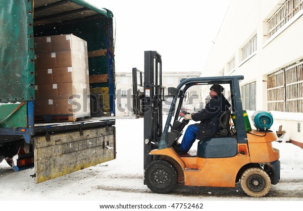 warehouse forklift loader loading cardboard\
boxes into a car\
outdoors
