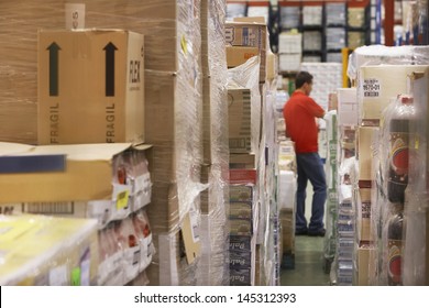 Warehouse Full Of Cellophane Wrapped Goods With Man In The Background