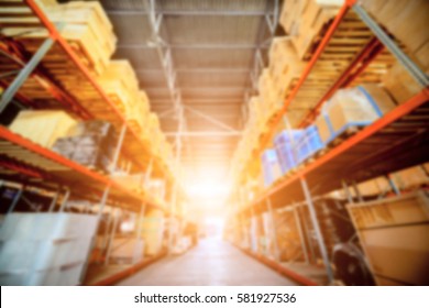 Warehouse industrial and logistics companies. Commercial warehouse. Boxes and crates stocked on the shelves of three storey. Bright sunlight. Deep blur effect.