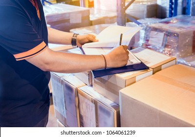 Warehouse inventory management. Warehouse worker is writing on clipboard with checking inventory of products in warehouse factory. - Powered by Shutterstock