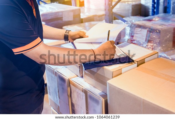 Warehouse inventory management. Warehouse worker\
is writing on clipboard with checking inventory of products in\
warehouse factory.