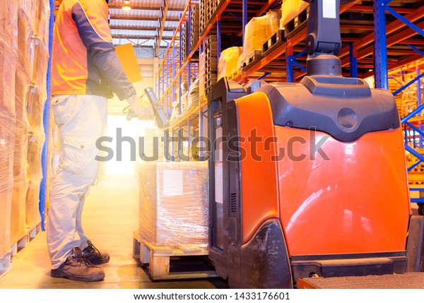Warehouse inventory management. Young man\
worker is scanning barcode scanner with shipment pallet, electric\
forklift pallet jack in\
warehouse.