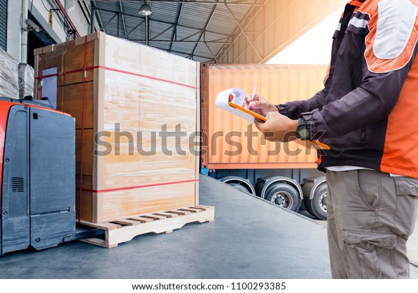 Warehouse loader holding clipboard with checking a\
pallet  for loading into a\
truck