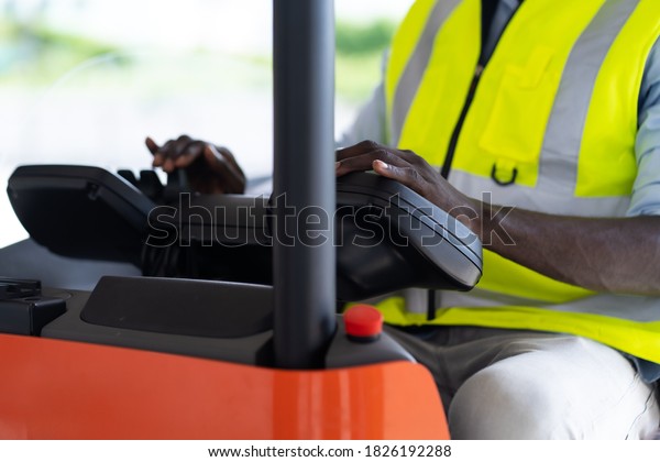Warehouse man worker driver forklift. warehouse\
worker driver stacking card boxes by forklift in warehouse store.\
African American black\
people.