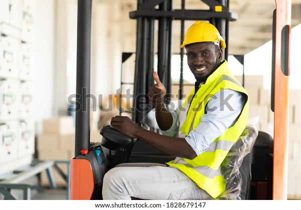 Warehouse man worker driver forklift. warehouse\
worker driver stacking card boxes by forklift in warehouse store.\
African American black\
people.