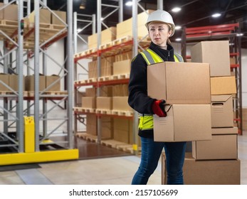 Warehouse manager. Girl to in large logistics center. Warehouse manager carries boxes. Woman in yellow vest and white protectors. Career concept in modern warehouse. Storage company worker. - Powered by Shutterstock