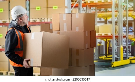 Warehouse Manager. Man In Logistics Center. Warehouse Manager Carries Boxes. Guy In Yellow Vest And White Helmet. Career In Modern Warehouse. Storage Company Worker. Selective Blurred.