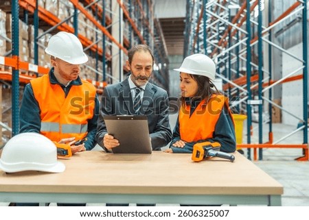Warehouse manager presenting an inventory report on a clipboard while engaging with warehouse workers in a collaborative discussion