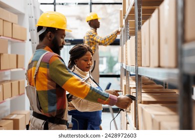 Warehouse manager supervising assistant scanning parcel barcode and pointing at cardboard box on shelf. African american storehouse worker using scanner on package and working with supervisor - Powered by Shutterstock