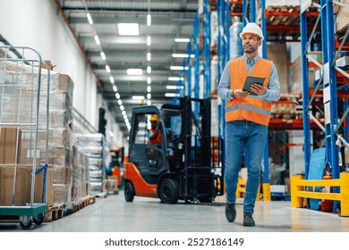 Warehouse manager using digital tablet is walking through warehouse and checking inventory, in background forklift is passing by - Powered by Shutterstock