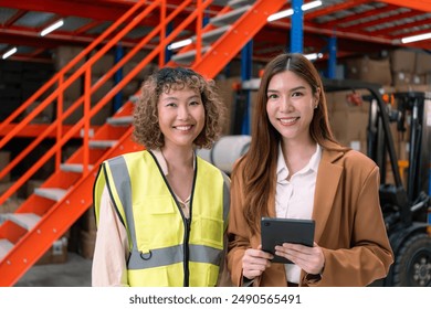 Warehouse manager and worker, the manager holding a tablet and the worker wearing a safety vest, stand in a warehouse. - Powered by Shutterstock