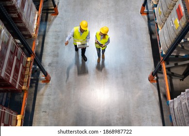 Warehouse Managers Consult Plans Using Laptop, Above View