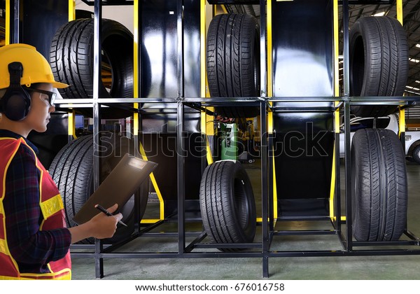 Warehouse managers people  with\
clipboard in reflective safety vest at  car tires warehouse\
.