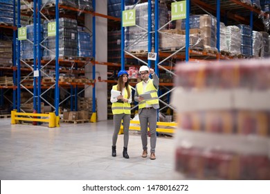 Warehouse Managers Walking Through Large Warehouse Distribution Center Discussing About Increasing Productivity.