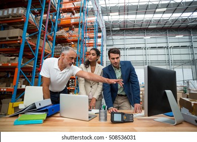 Warehouse Managers And Worker Discussing With Computer In Warehouse Office