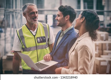 Warehouse Managers And Worker Discussing With Laptop In Warehouse Office