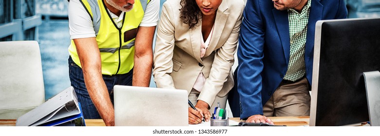 Warehouse Managers And Worker Discussing With Laptop In Warehouse Office