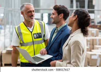 Warehouse Managers And Worker Discussing With Laptop In Warehouse Office