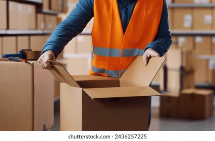 Warehouse operative opening a carton box, logistics and distribution concept - Powered by Shutterstock