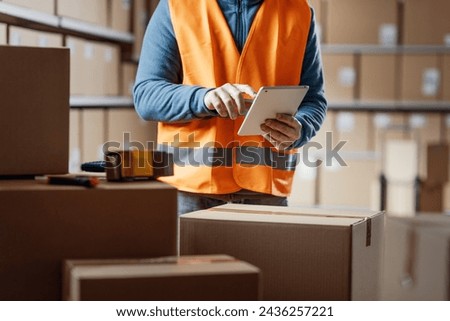 Warehouse operative using a digital tablet and preparing shipments, distribution and logistics concept
