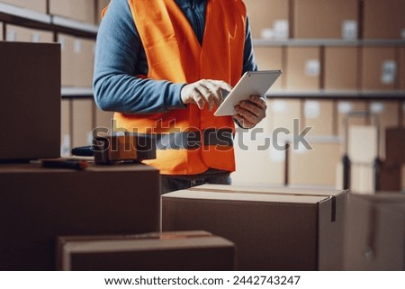 Warehouse operative using a digital tablet and preparing shipments, distribution and logistics concept