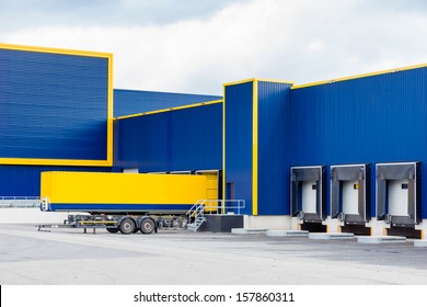 warehouse painted yellow and blue with a trailer in front