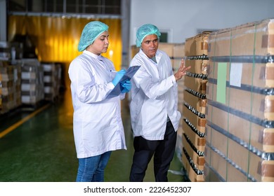 In warehouse quality control team checking drinking bottle stack on pallet before delivery