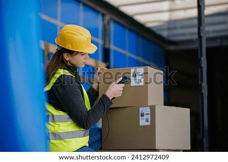 Warehouse receiver kneeling inside of truck in cargo area, trailer, barcode scanning delivered items. Receiving clerk holding scanner checking delivered goods against order.