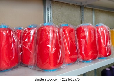 Warehouse with skeins of colored red threads on shelves of high racks. shelf of haberdashery with lots of threads, yarn. Repository textile factory, garment wholesale trade store for sewing. - Shutterstock ID 2223655575