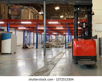 Warehouse Storage Of Retail Merchandise Shop, Worker Driver In Uniform Loading And Unload Cardboard Boxes By Forklift Stacker For Loader In A Large Modern Warehouse