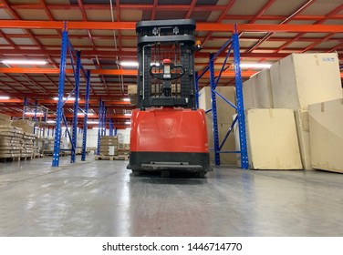 Warehouse Storage Of Retail Merchandise Shop, Worker Driver In Uniform Loading And Unload Cardboard Boxes By Forklift Stacker For Loader In A Large Modern Warehouse