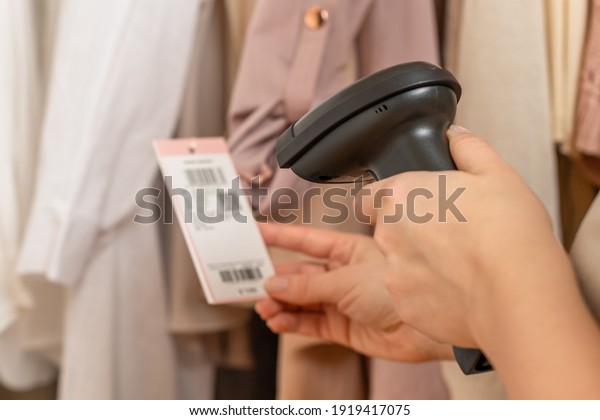A warehouse woman employee accepts\
clothes using barcode scanner reading a bar code from price tag of\
female blazer and adds to the computer base.  \
