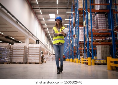 Warehouse Woman Worker Confidently Walking Through Large Warehouse Storage Center And Organizing Distribution. Successful People At Job.