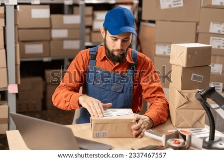 Warehouse worker applying shipping label on parcel boxes. Copy space
