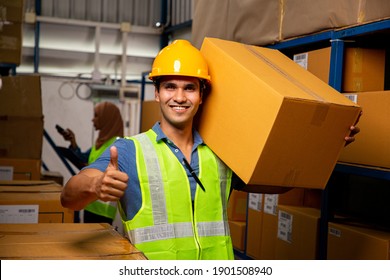 Trabajador de almacén cargando una caja para su entrega a las existencias de producción. Personal indio con chaleco reflexivo y casco amarillo sonriendo para la felicidad con su trabajo. Gente asiática en lugar de trabajo.