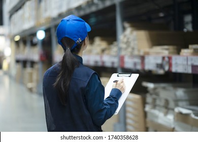Warehouse worker checking inventory with clipboard in logistics warehouse