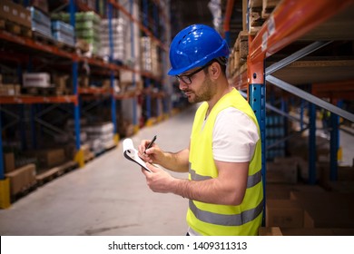 Warehouse worker checking inventory in large distribution center. Controlling goods storage and distribution.